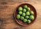 Mini kiwis Actinidia arguta on an stoneware plate on a rustic kitchen table