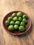 Mini kiwis Actinidia arguta on an stoneware plate on a rustic kitchen table