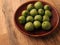 Mini kiwis Actinidia arguta on an stoneware plate on a rustic kitchen table