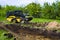 Mini loader with grassy soil in bucket during earth works in countryside