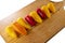 Mini multicolored peppers, aligned on a wooden cutting board