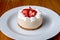 Mini New York cheesecake with strawberries on a white plate on a wooden table