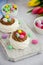 Mini Pavlova Birds Nest with chocolate cream and colored candy on a board on a light background. Merengue Cookies.