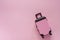 Mini pinky luggage toy model on pink pastel colored background