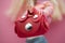 mini red leather bag in hand of blond mannequin doll on pink background