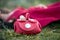 mini red leather hand bag in hands of mannequin doll lying in the grass in a public garden