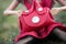 Mini red leather hand bag in hands of mannequin doll sitting in the grass in a public garden