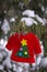 Mini red ugly sweater with Christmas tree hanging in snow covered bush