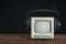 Mini retro TV with headphones on wooden table on black background.