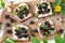Mini sandwiches with black bread, cottage cheese and jam of berries on rustic cutting board on a white wooden table.Top view