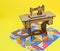 Mini sewing machine, made of wood, on a patchwork rug, with yellow background