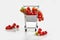 Mini shopping cart full with cherry tomatos on white background