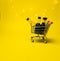 Mini shopping cart full of small alcohol bottles yellow background