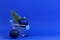 Mini shopping cart with small Christmas tree and navy Christmas decoration bauble balls on blue background