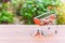 Mini Shopping Cart or Trolley For Retail Business Filled with Bronze Coins Isolated on Wooden Table