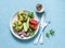 Mini spinach cheddar frittata and vegetables salad on blue background, top view. Breakfast, snack, appetizers