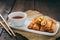 Mini spring rolls with sweet spicy dip and chopsticks on a rustic wooden table