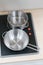 Mini stainless steel pot and pan on black electric stove over wo