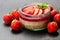 Mini strawberry cheesecake in a glass pot on black stone backgr