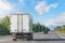 Mini truck driving on highway on sunny day. White modern delivery small shipment cargo courier truck moving fast on motorway road