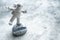 Miniature astronaut balancing on moon in spacesuit waving his hand.