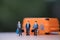 Miniature businessman carry bag standing front orange suitcase