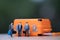 Miniature businessman carry bag standing front orange suitcase