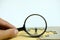 Miniature businessman standing behind magnifier glass in the middle of jigsaw puzzle