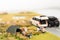 Miniature campers on grassland with vehicles on the road
