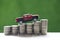 Miniature car model on growing stack of coins money on nature green background  Saving money for car  Finance and car loan