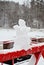Miniature cute snowman made of natural snow on background of snowy park