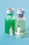 A miniature doctor standing on front of two vials with medicine in it