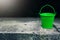 Miniature empty green bucket on cement stand. Sunshine
