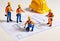 Miniature figures construction workers working on a blueprint. Suitable for architectural concepts, engineering designs