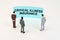 Miniature figures of people stand in front of a blue sign with the inscription - Critical Illness Insurance