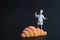 Miniature figurine of a cook with a giant croissant on a black background