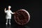 Miniature figurine of a cook with a giant stuffed biscuit on a black background