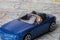 Miniature figurine of a man driving a convertible blue car on a street map