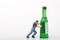 Miniature figurine of a man pushing a giant bottle of alcoholic drink