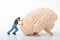 Miniature figurine of a man pushing a giant brain