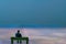 Miniature figurine posed as man sitting alone on a bench in surreal scener