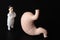 Miniature figurine of a surgeon with a giant stomach a black background