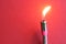 Miniature gas burner made of a metal reinforced hose on a red background. Fire and fire safety. Gas leak hazard concept