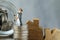 Miniature happy couple family standing on stack of coins as prop