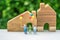 Miniature happy family holding balloons with wooden house as pro