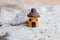 A miniature house and a landscape of white sand with stone and shells. Small toys