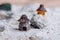 A miniature house and a landscape of white sand with stone and shells. Small toys