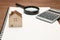 Miniature house, magnifying glass, calculator on blank notebook.