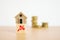 Miniature house on less percent icon on wood cube and blurred stack of coins on wooden desk , for decreasing interest, lower