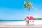 Miniature house with red roof on tropical sand beach over blurred cloudy sky on day noon light.Image for property real estate inve